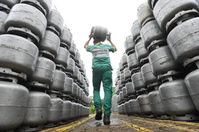 Entregador Liquigás carregando um botijão na unidade de distribuição